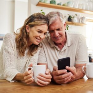 Senior couple on smartphone reading online social media post, search holiday house website or retir