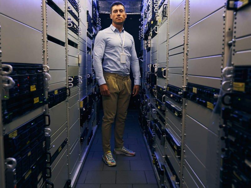 Serene IT worker standing alone among server racks